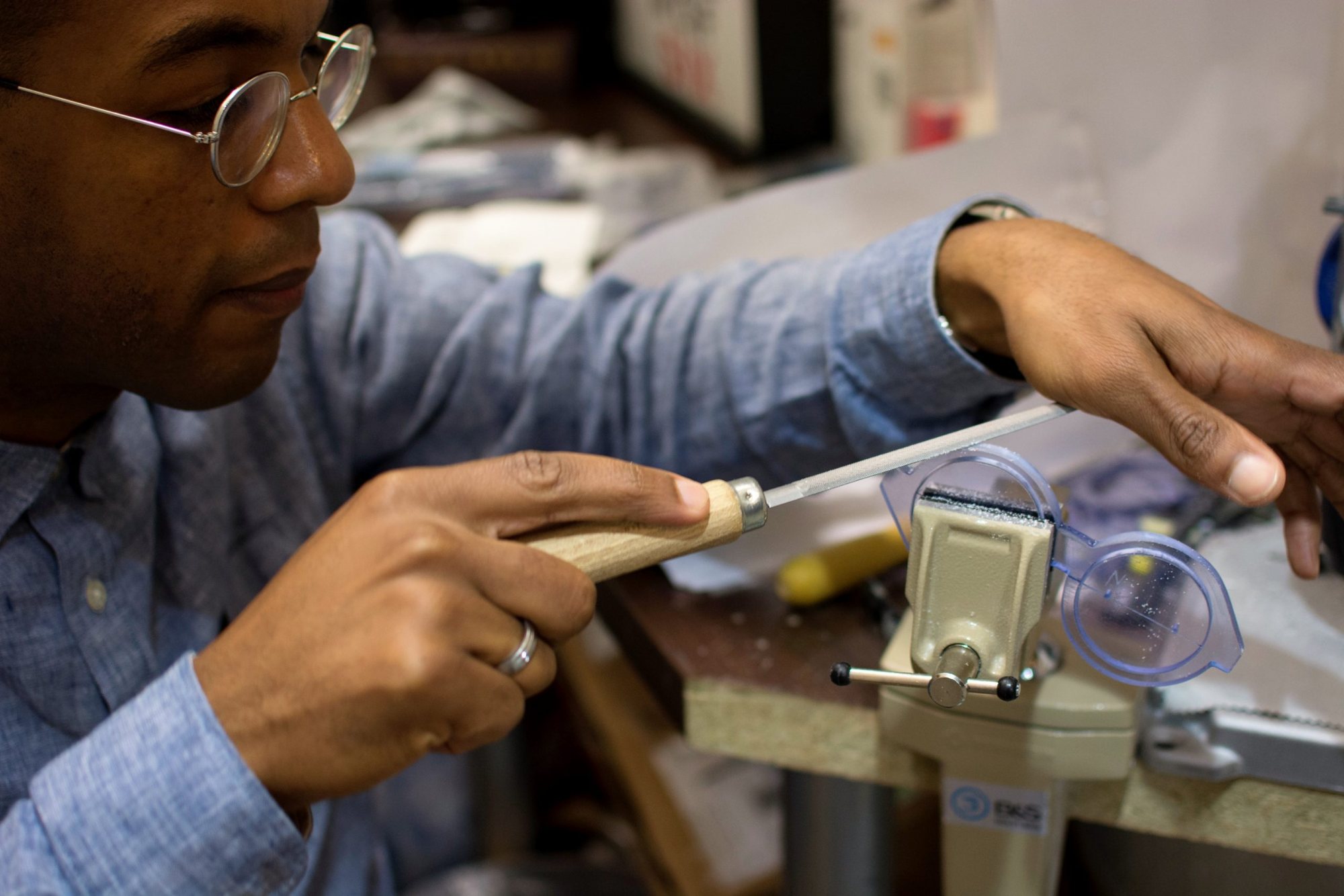Artisan limant une monture de lunettes serrée dans un étau