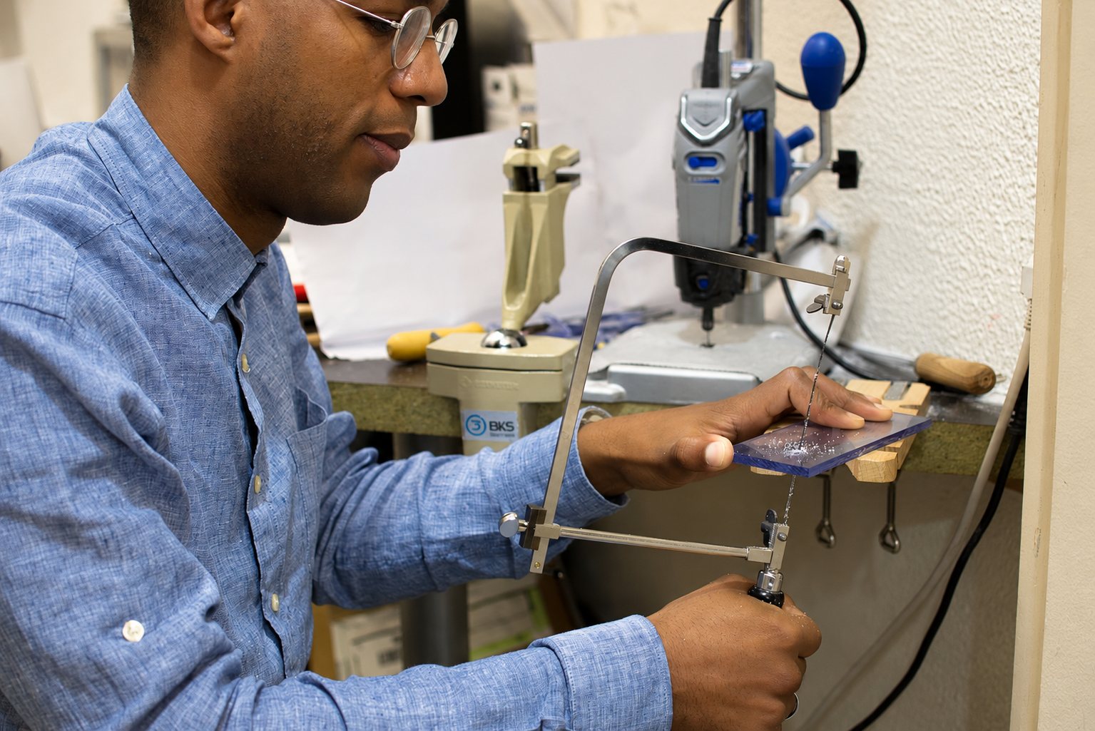 Artisan sciant une plaque avec une scie à chantourner