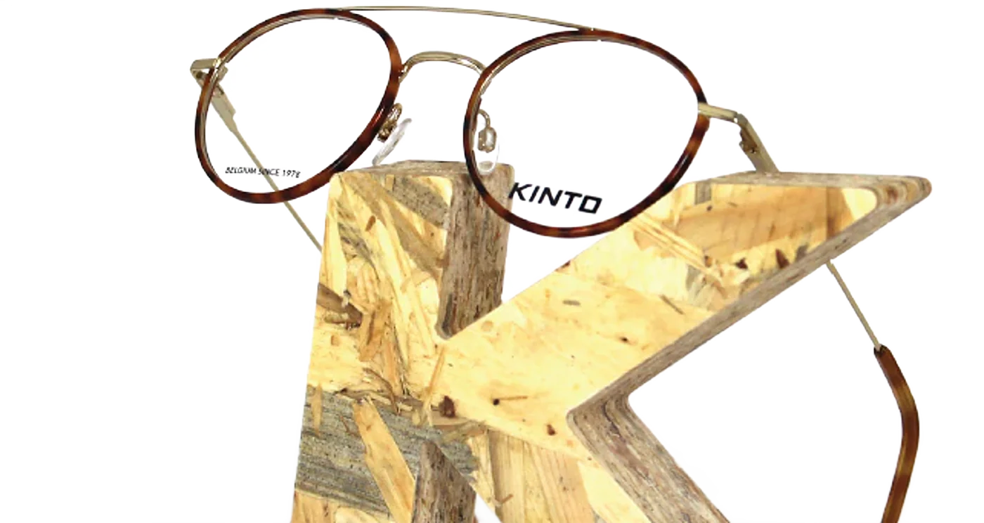 Lunettes rondes en écaille et métal doré posées sur un K en bois